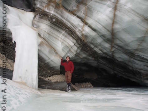 Posing next to a frozen waterfall at the eastern Ice cave of Castner Glacier. Behind me, the cave extends far back. Look at those layers of ice and sediment! Each represents at least a winter of ice. I am literally standing underneath thousands of years of ice history!